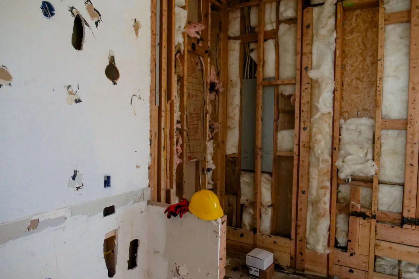 A room stripped to the studs with old batt insulation exposed in the cavities